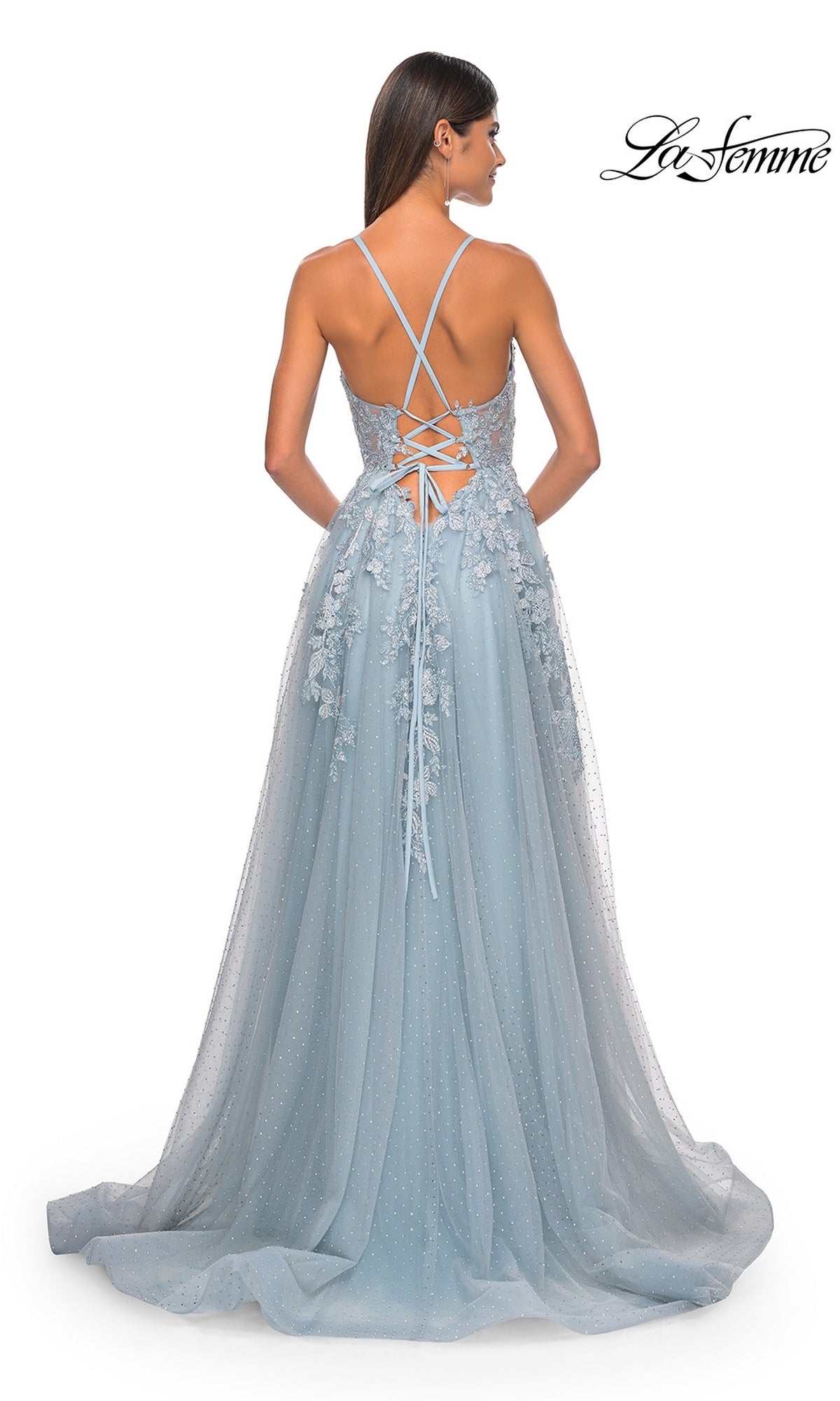 A woman is seen from behind wearing the La Femme Lace-Embroidered Long Prom Dress 32147 in light blue, which features thin shoulder straps, a lace-up back, and embroidered floral lace appliqué details.